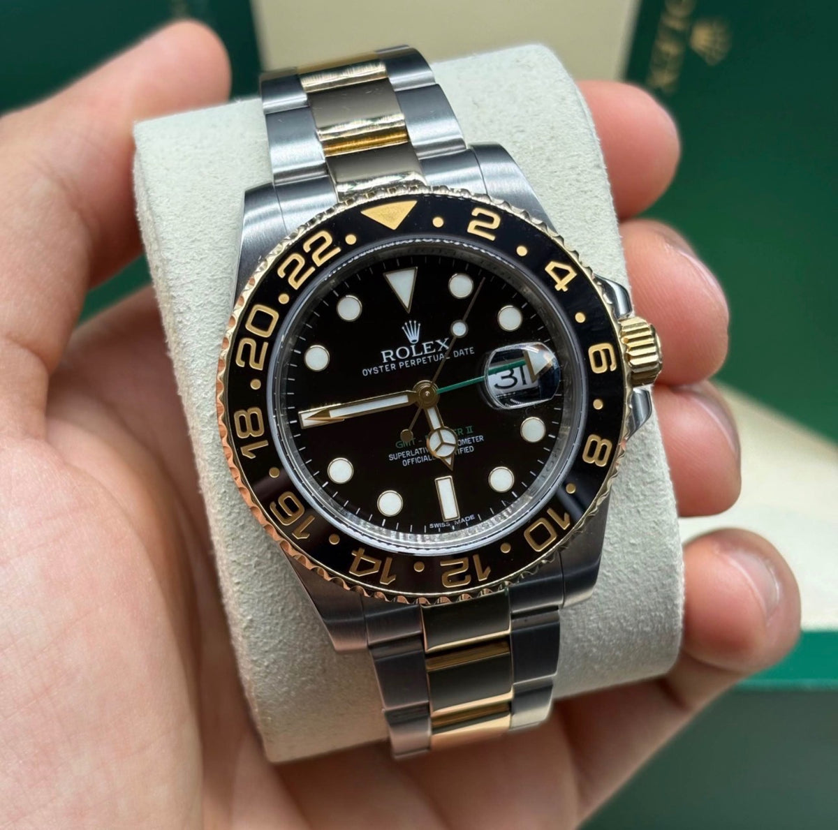 Rolex GMT Master II 116713 two tone steel and 18K yellow gold black dial held in hand, showing the green GMT hand and gold numeral ceramic bezel at Adonia Jewellers in Yorkville, Toronto