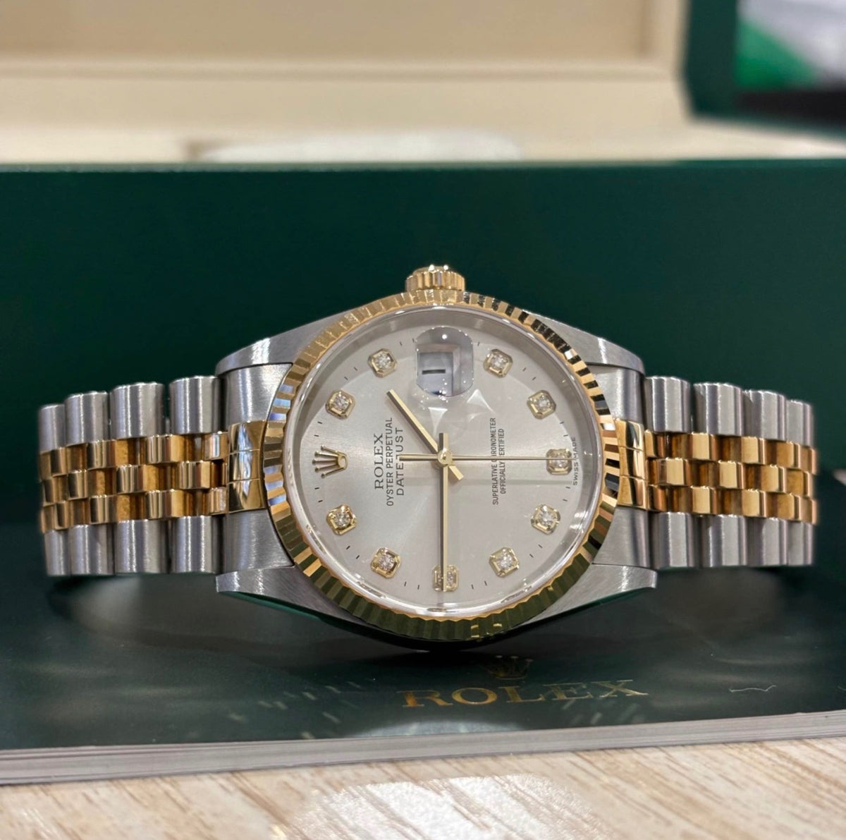 Rolex Datejust 36 silver diamond dial angled view showing the fluted yellow gold bezel and date Cyclops