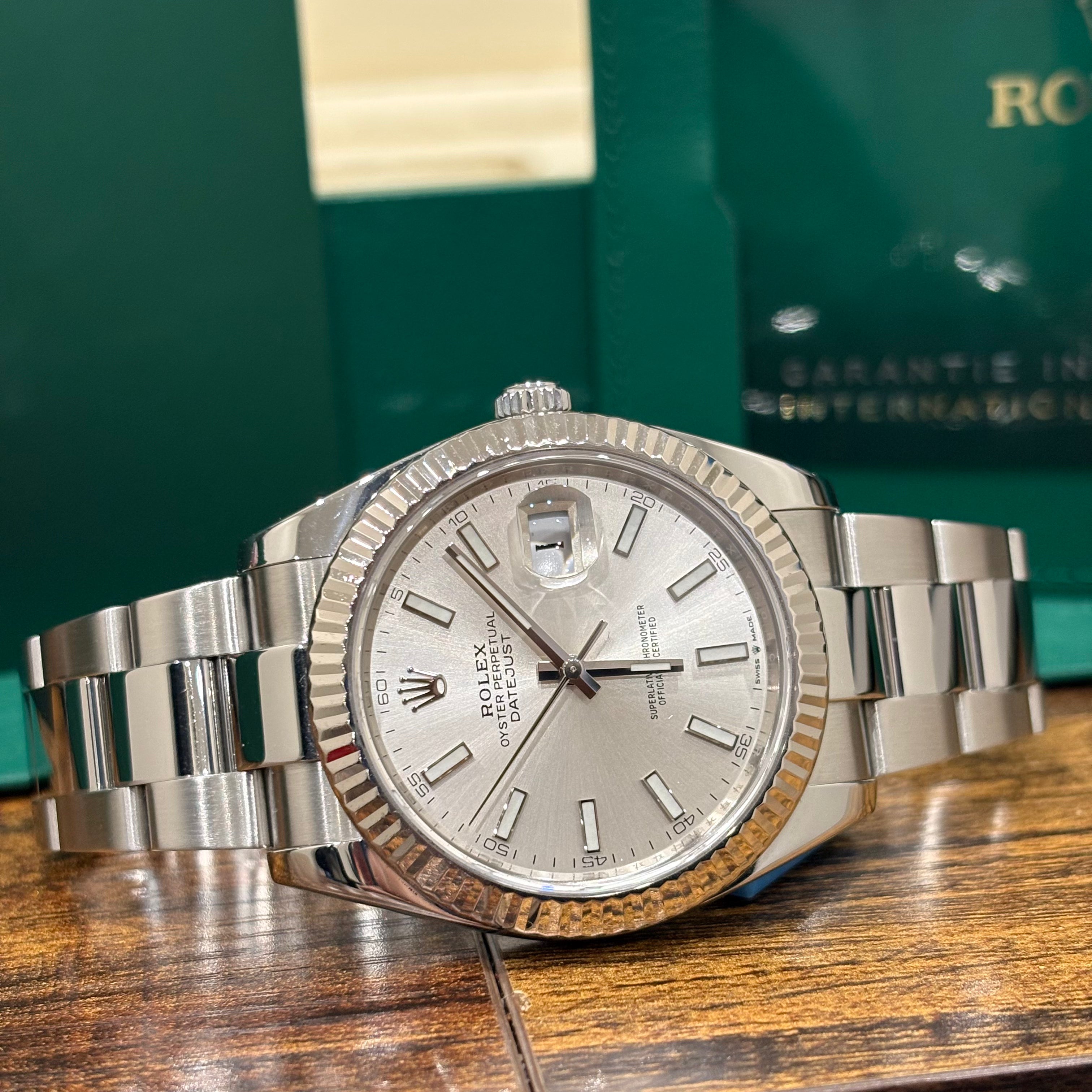 Rolex Datejust 41mm silver dial side on view of the Oystersteel Oyster bracelet on a wooden table