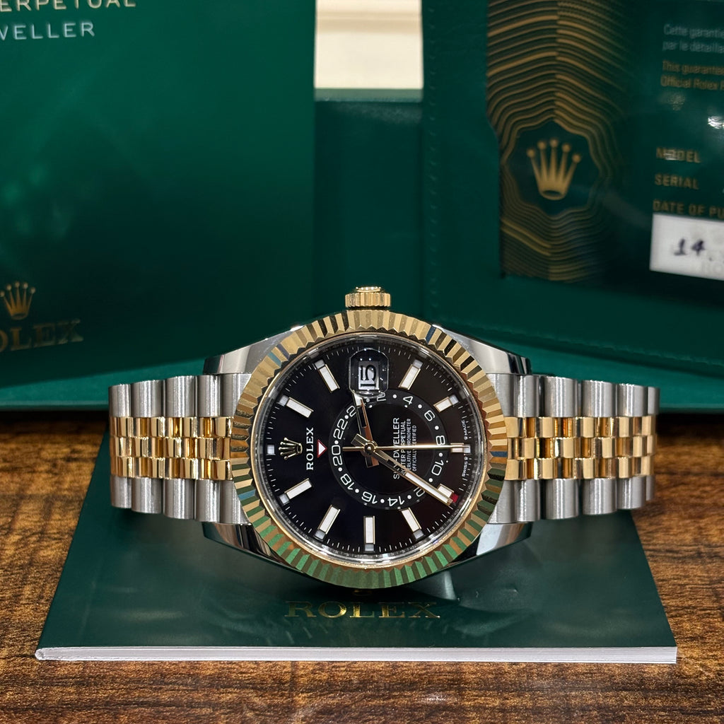 Rolex Sky Dweller 42mm two tone black dial resting on its Rolex booklet with the warranty card behind