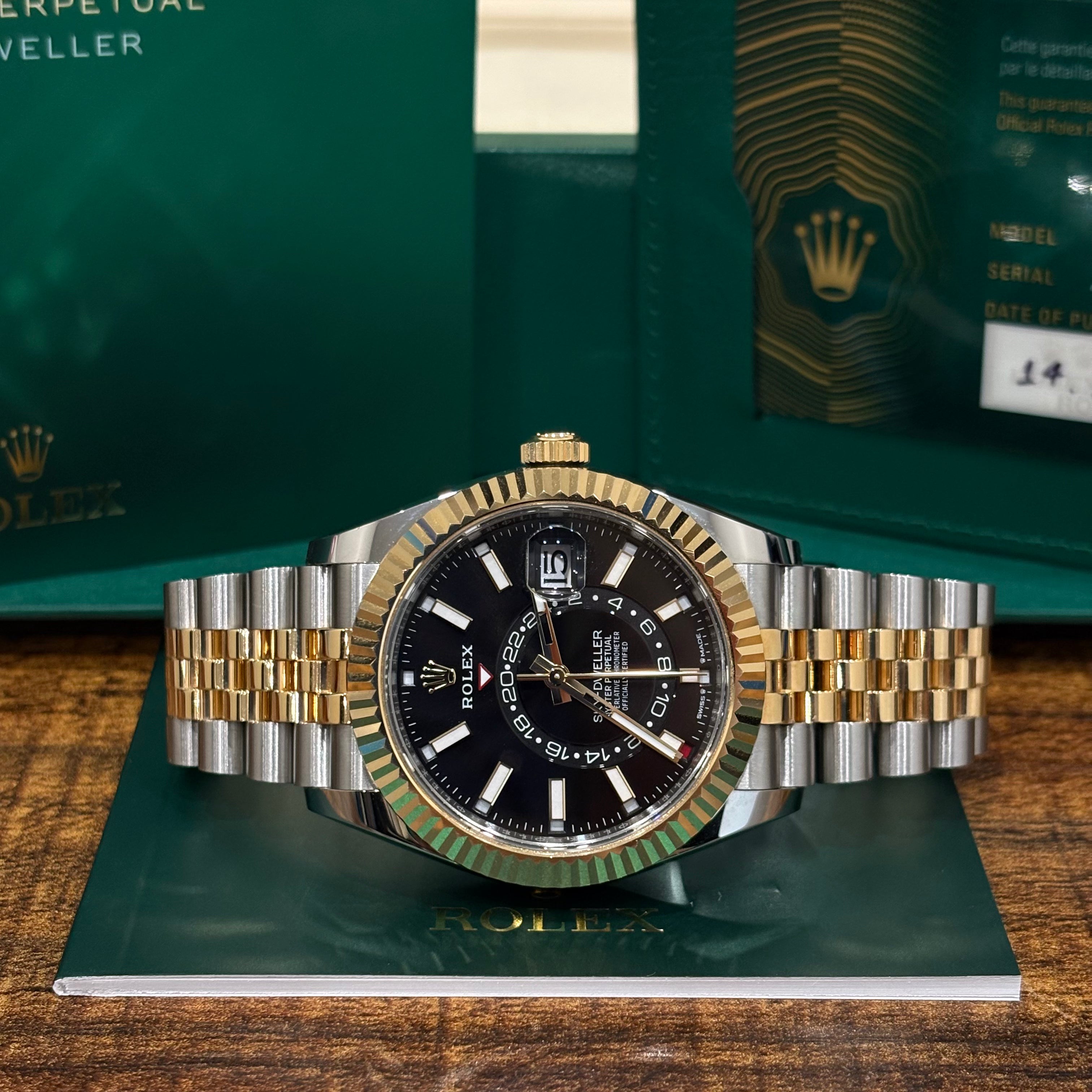 Rolex Sky Dweller 42mm two tone black dial resting on its Rolex booklet with the warranty card behind