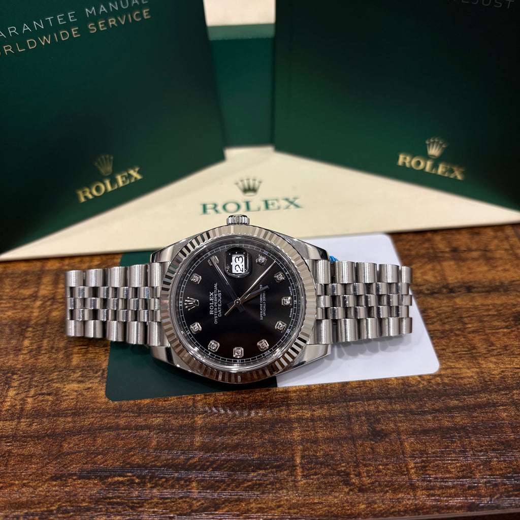 Rolex Datejust 41mm black diamond dial wide view on a wooden table with its Rolex warranty card