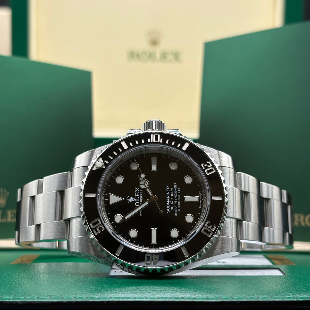 Rolex Submariner no date ref 114060 black dial and black Cerachrom bezel, laid flat in front of its Rolex box at Adonia Jewellers in Yorkville, Toronto
