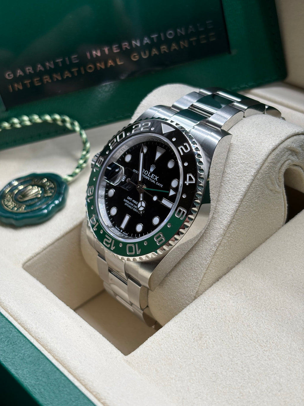 Rolex GMT Master II 2026 Sprite side view of the ceramic bezel with International Guarantee wallet behind