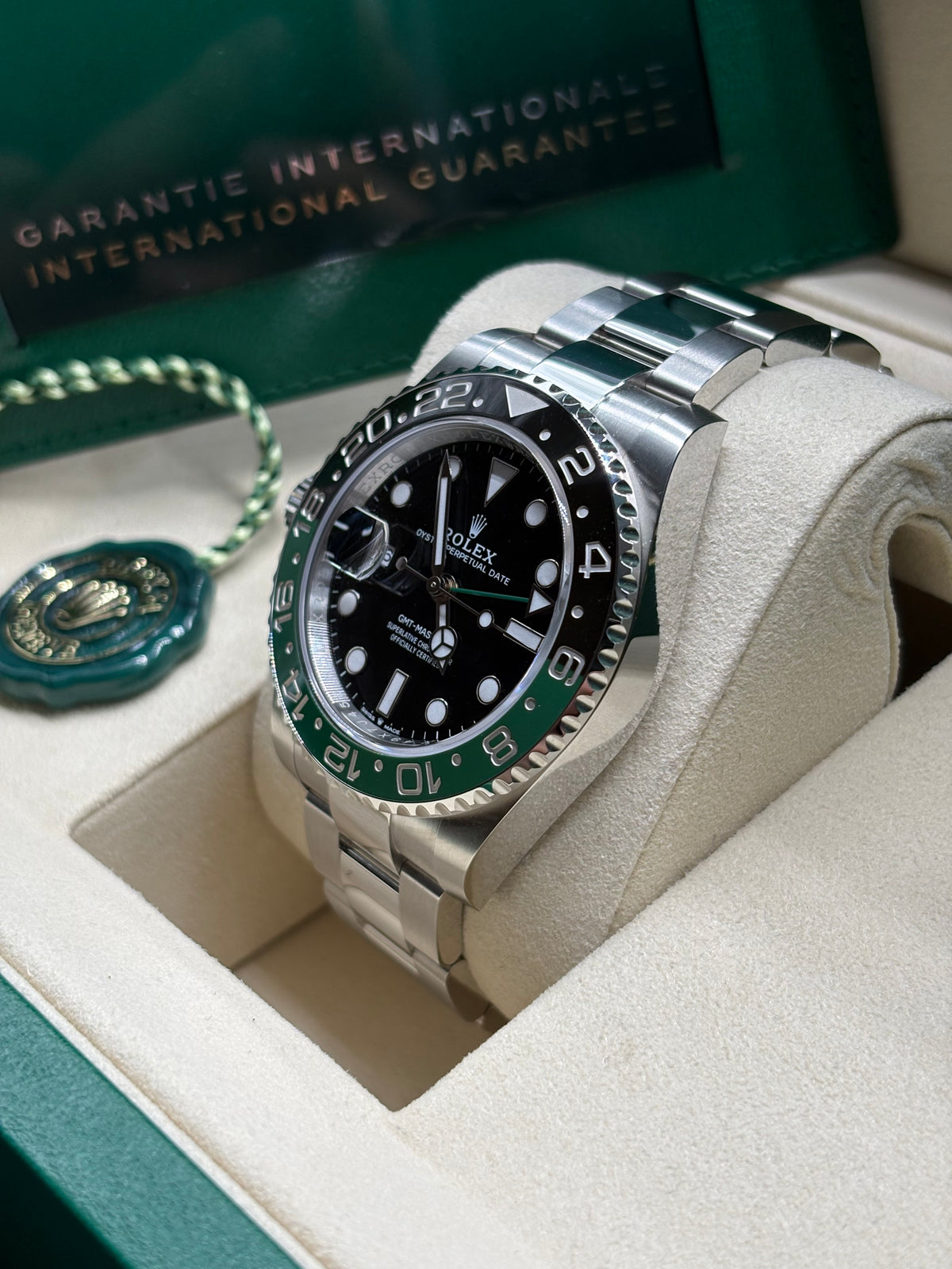Rolex GMT Master II 2026 Sprite side view of the ceramic bezel with International Guarantee wallet behind