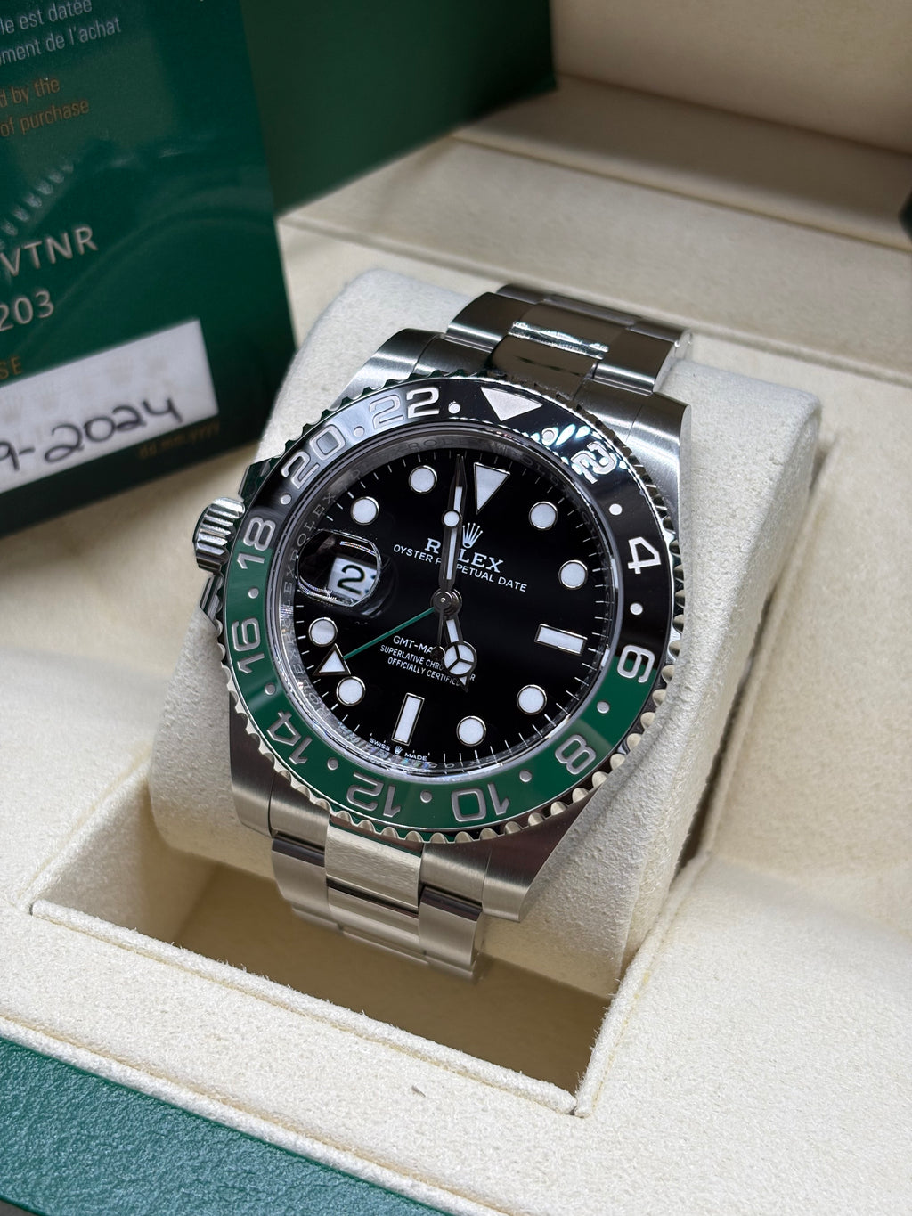 Rolex GMT Master II Sprite on its cushion with the 2024 dated warranty card behind