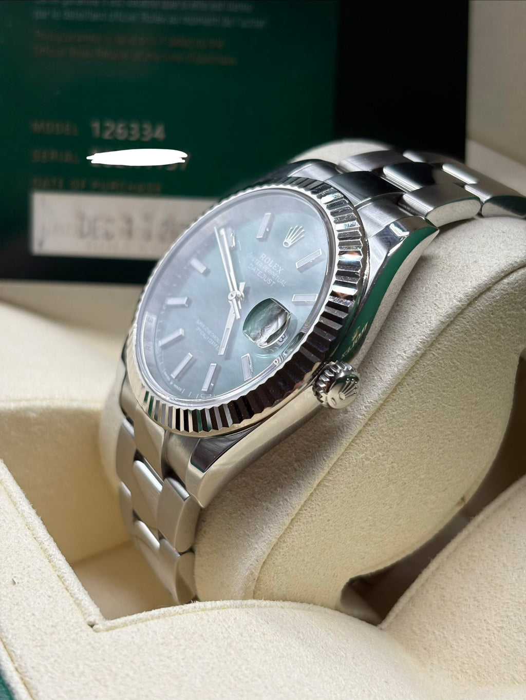 Rolex Datejust 126334 mint green dial side view showing the winding crown with the warranty card behind