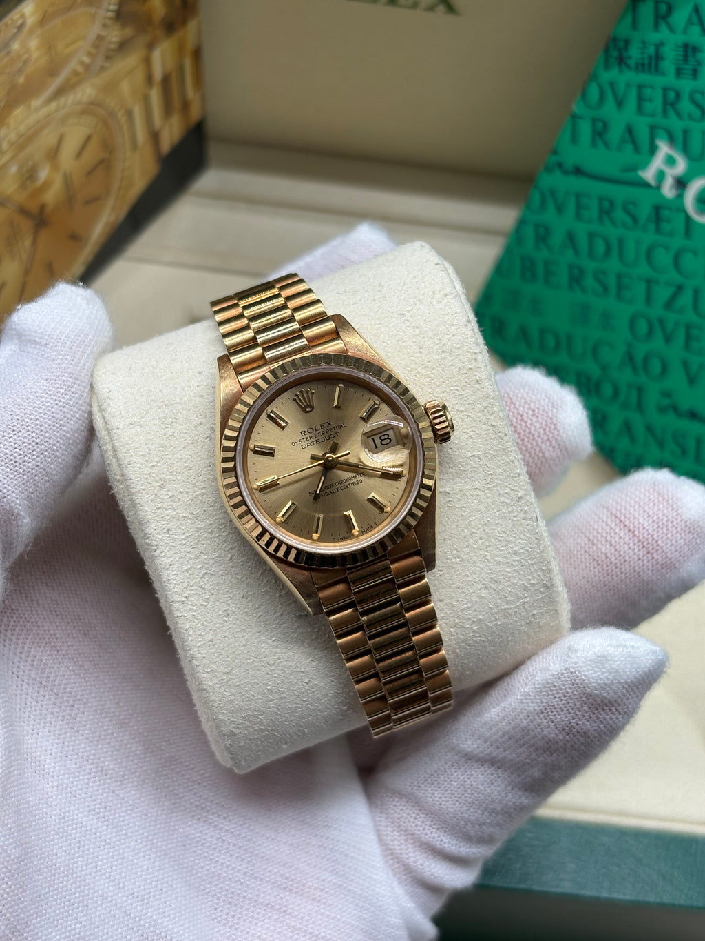 Rolex Lady Datejust 26mm 18K yellow gold champagne dial on President bracelet held in a white gloved hand at Adonia Jewellers in Yorkville, Toronto
