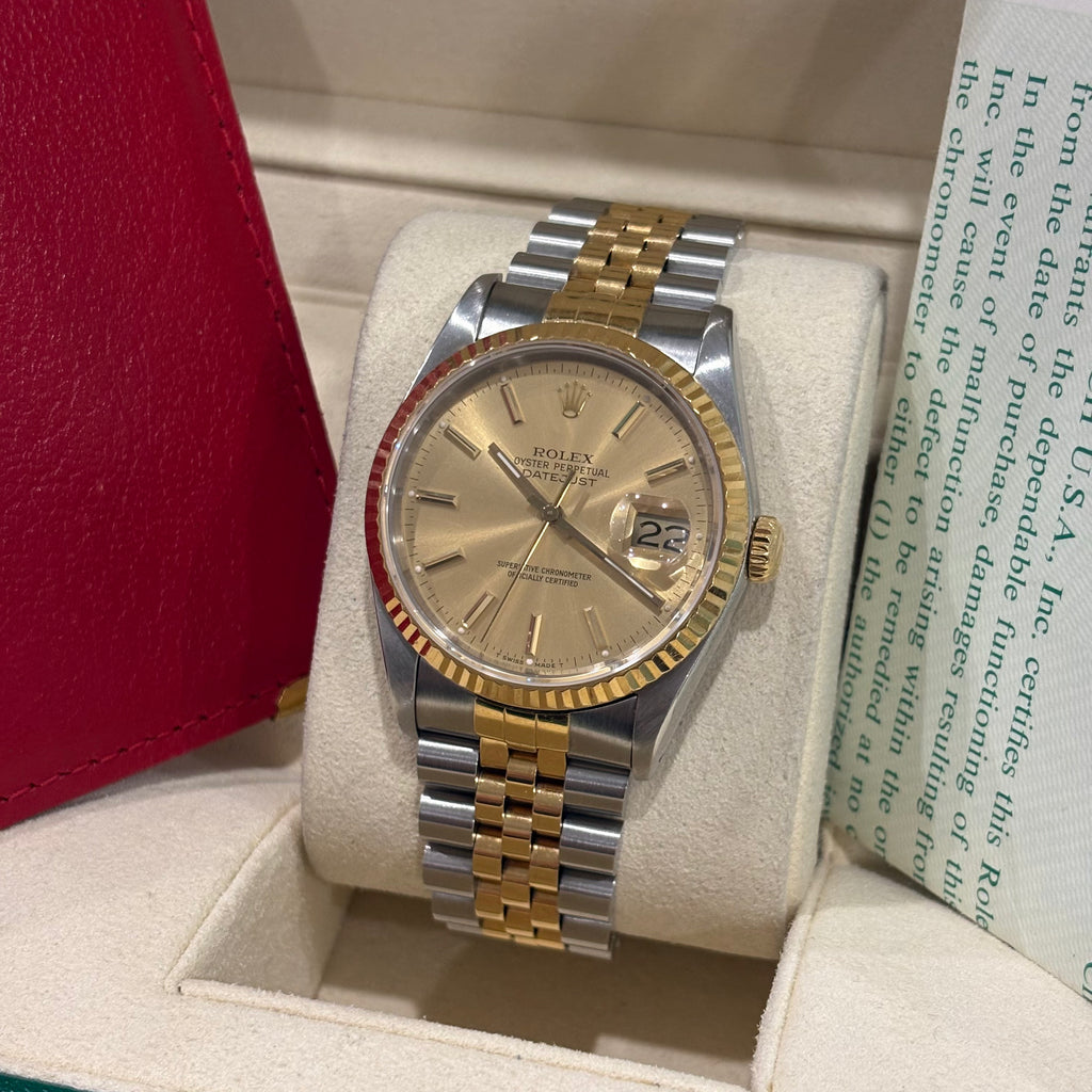 Rolex Datejust 36 two tone champagne dial three quarter view beside its red Rolex wallet